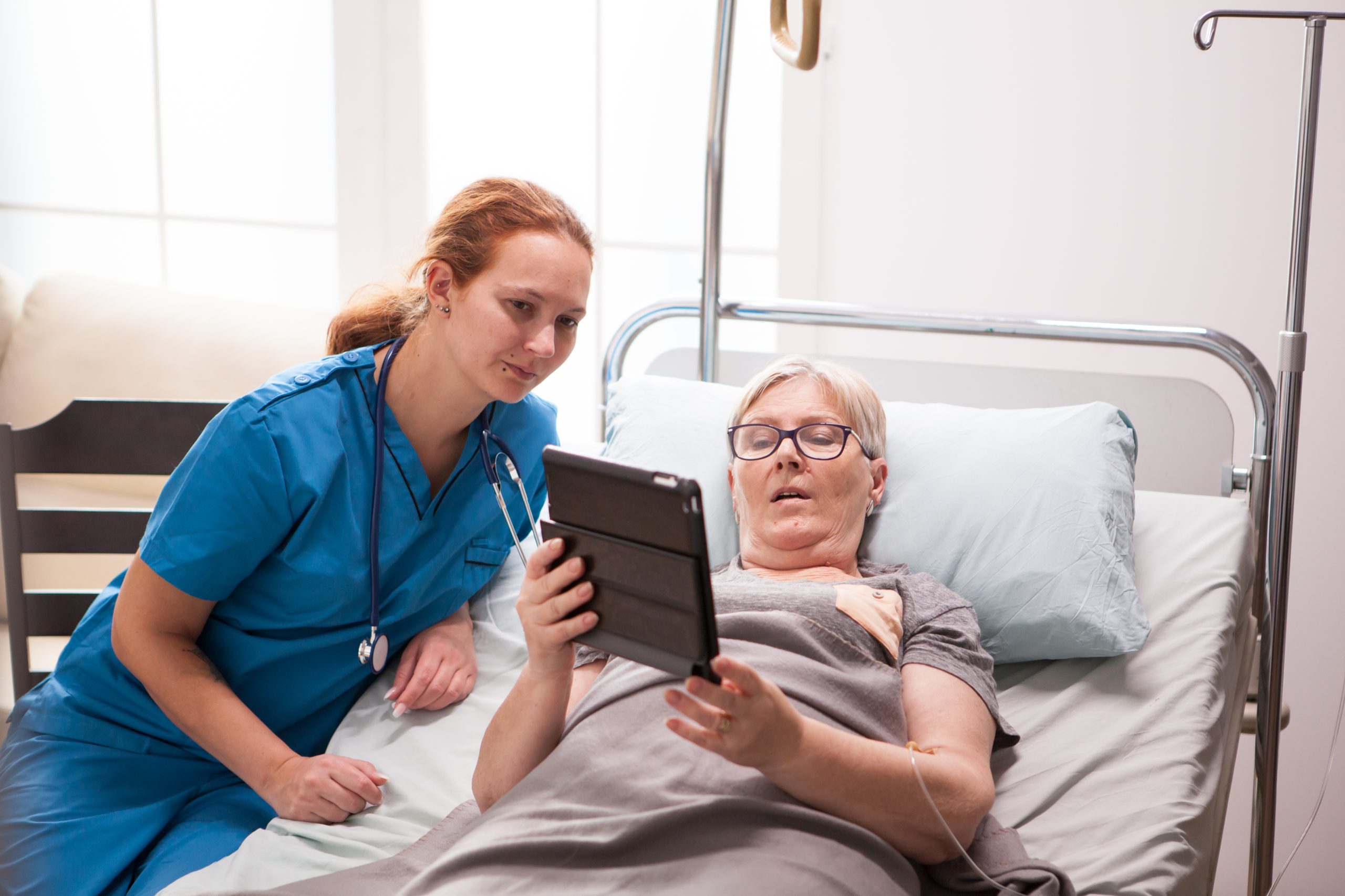 Portrait of old woman in nursing home using tablet computer Registered Nurse - Day and Night Shifts